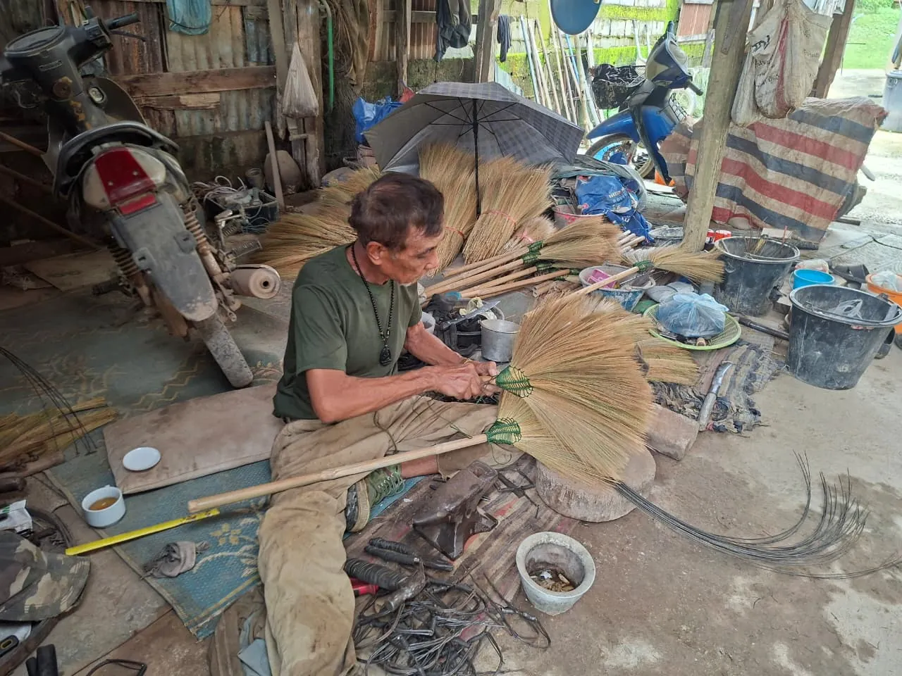 Khmu elder handcrafting traditional brooms