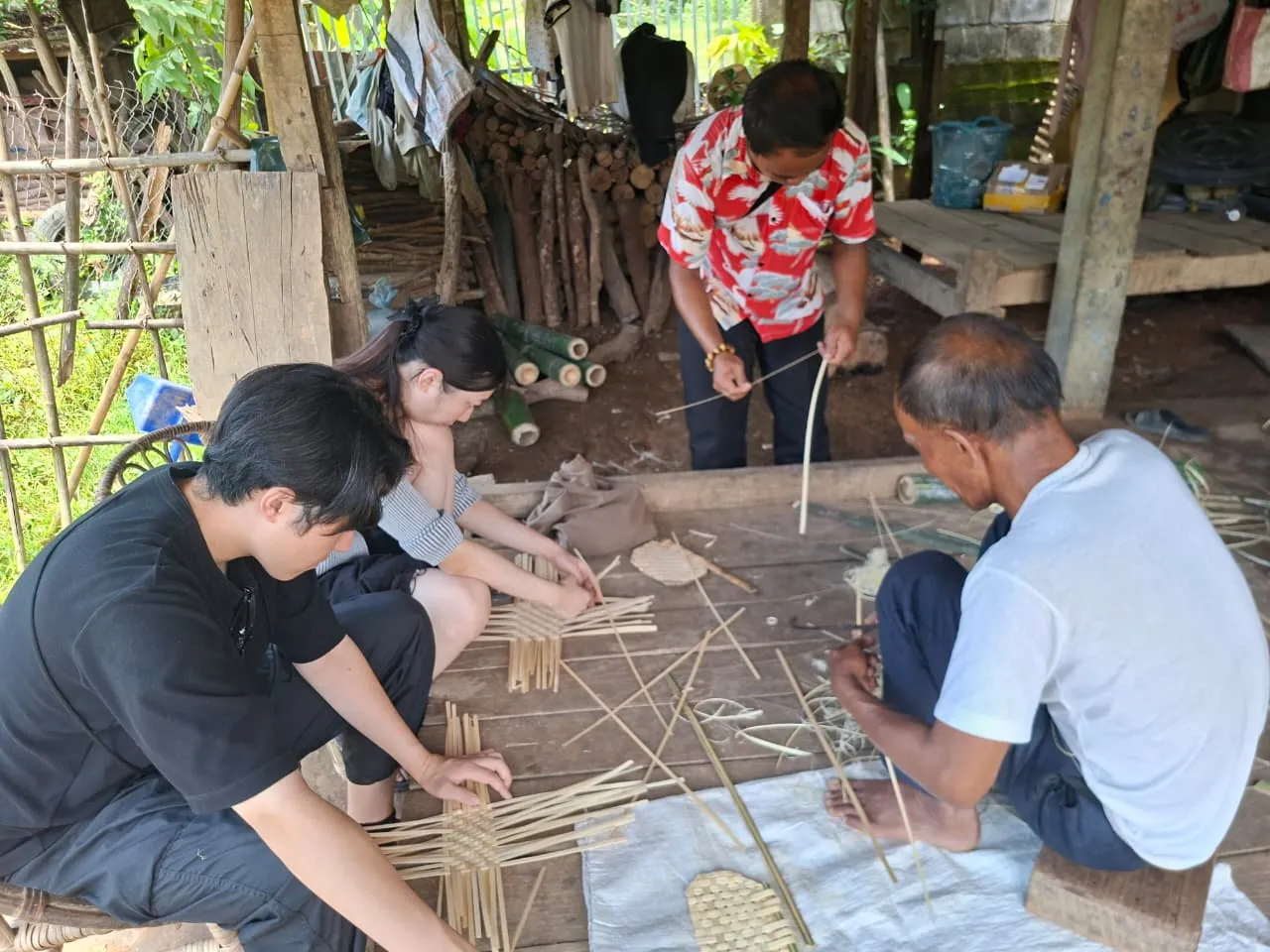 Visitors learning bamboo weaving with a Khmu elder