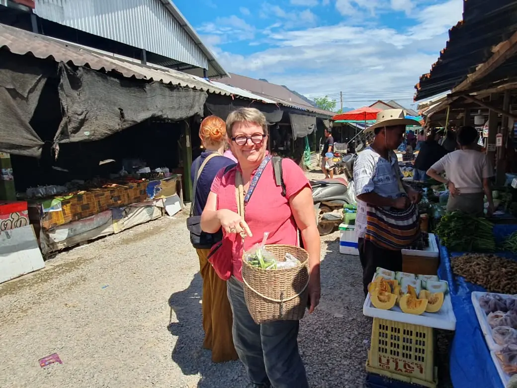 Traveler with a Khmu guide shopping at the Vang Vieng morning market