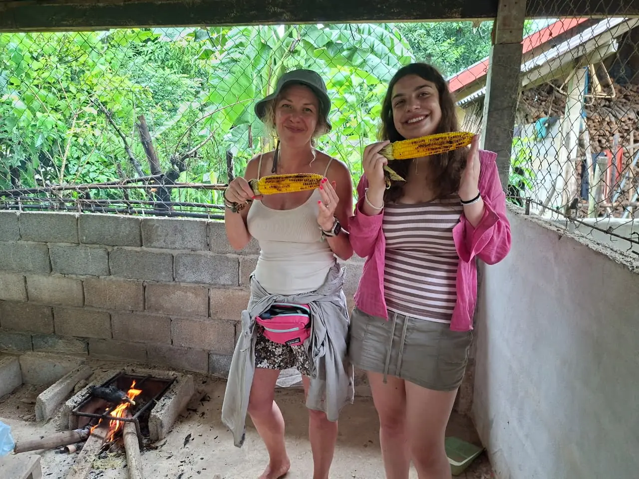 Guests with grilled corn by the wood fire