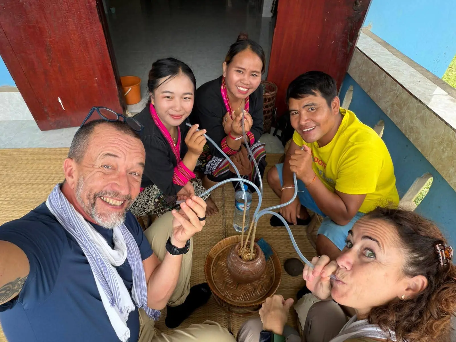 Guests and Khmu hosts sharing rice wine from the jar