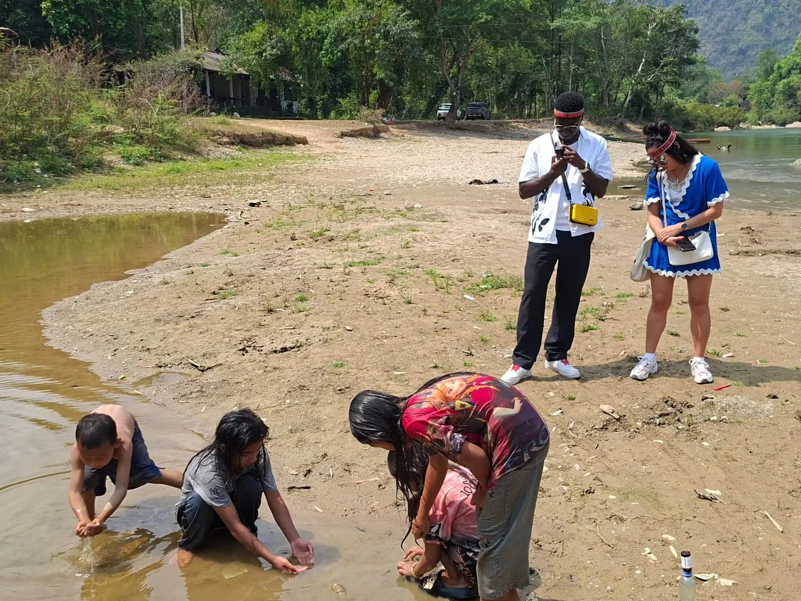 Village children playing in the river while guests watch